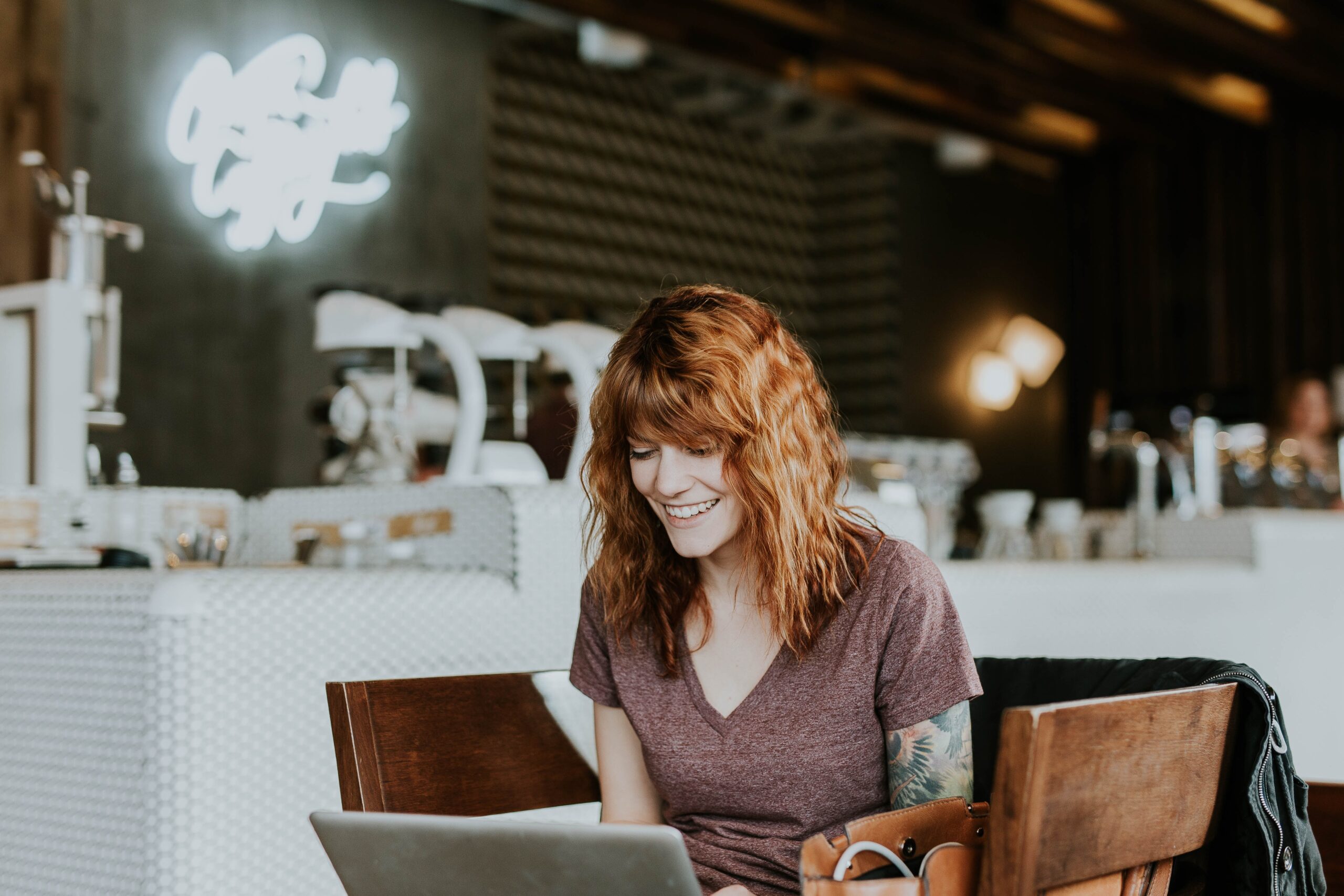 a woman smiling while sitting at a table with a laptop