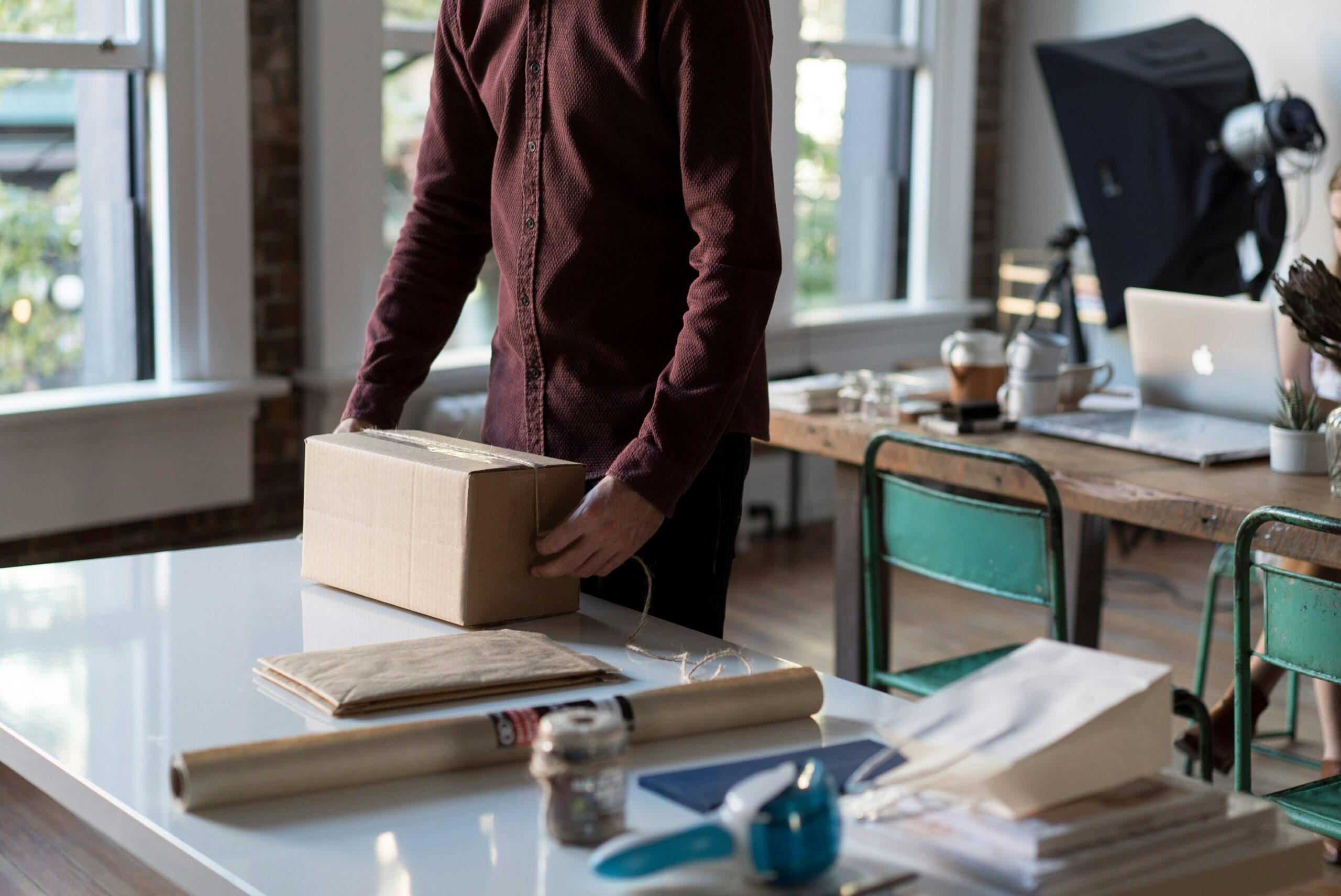 Person packaging a box with photo equipment in the background
