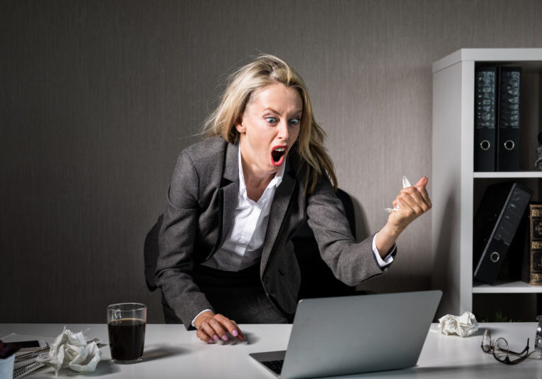 Furious employee yelling at her laptop computer at work