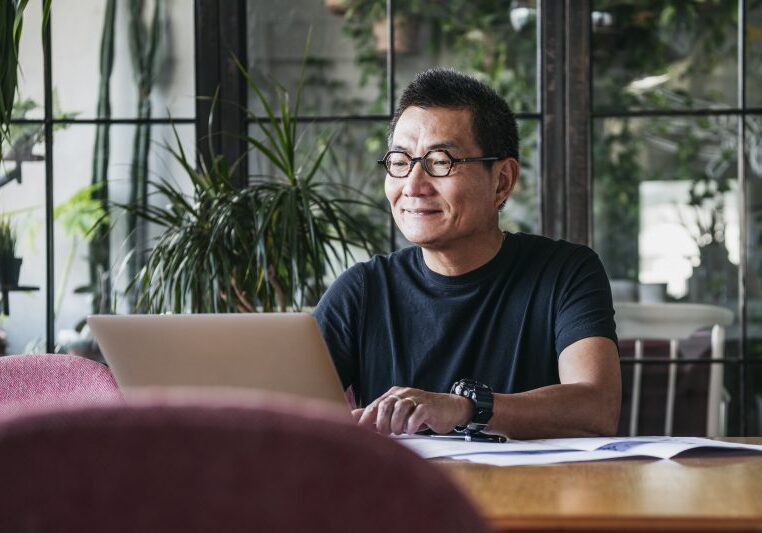 Smiling Chinese man working on laptop at home