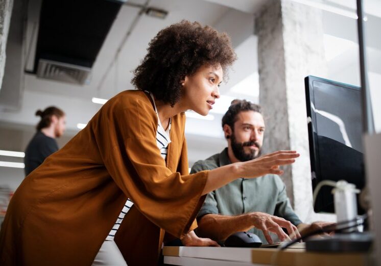 a woman showing a man something on a computer screen