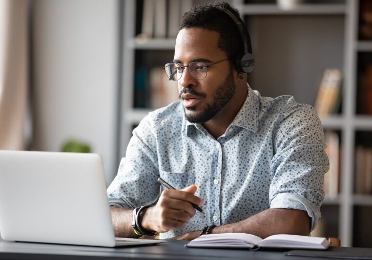 a man in front of a laptop, wearing headphones